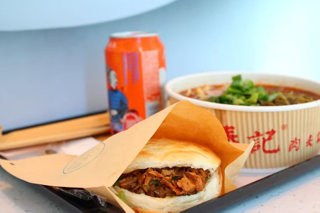 A delicious meal set featuring a roujiamo, a bowl of noodles or soup, and a canned drink.