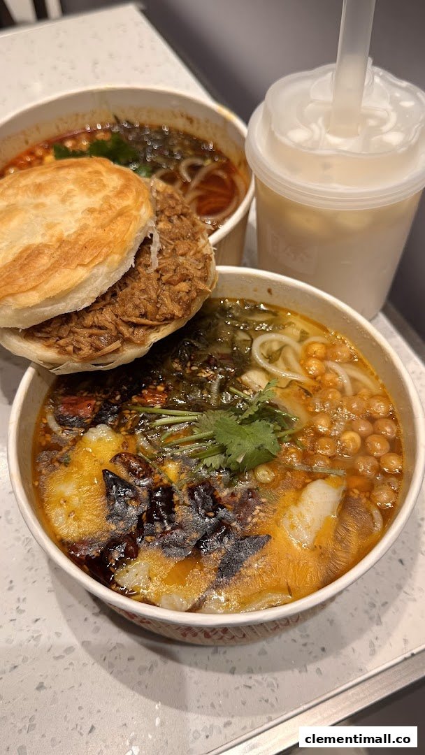 A delicious spread featuring a roujiamo, spicy noodles, and a refreshing drink on a counter.