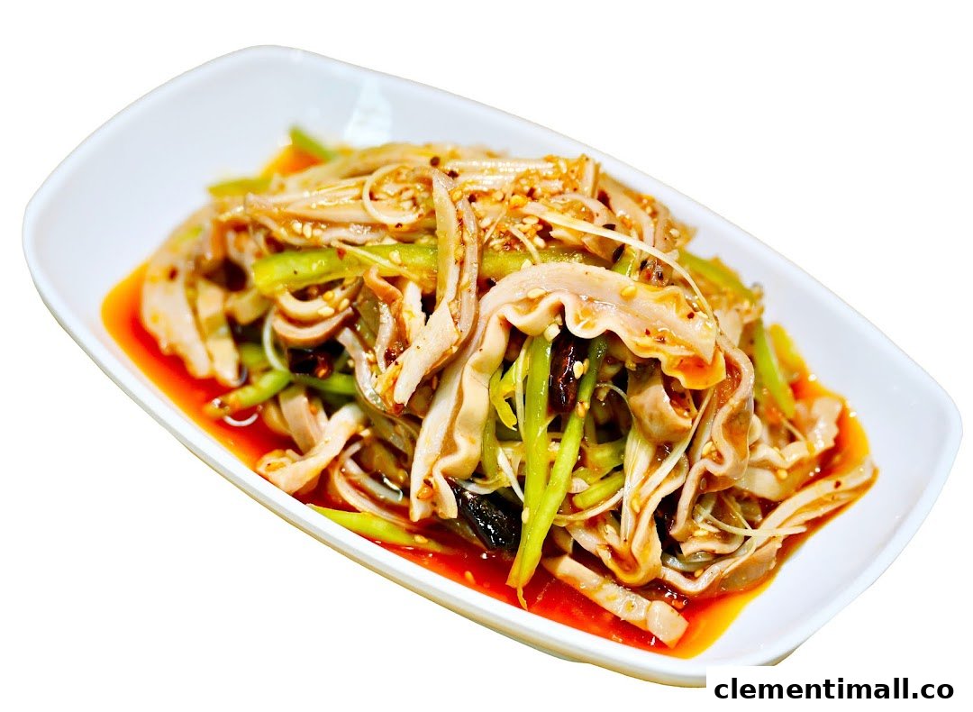 A spicy cold dish featuring sliced tripe, green vegetables, and sesame seeds in a red sauce.