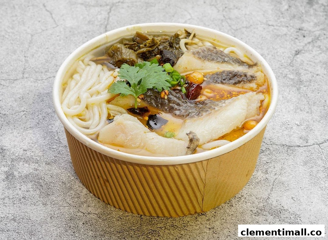 A close-up of a delicious bowl of noodles with fish fillets, pickled vegetables, and cilantro.