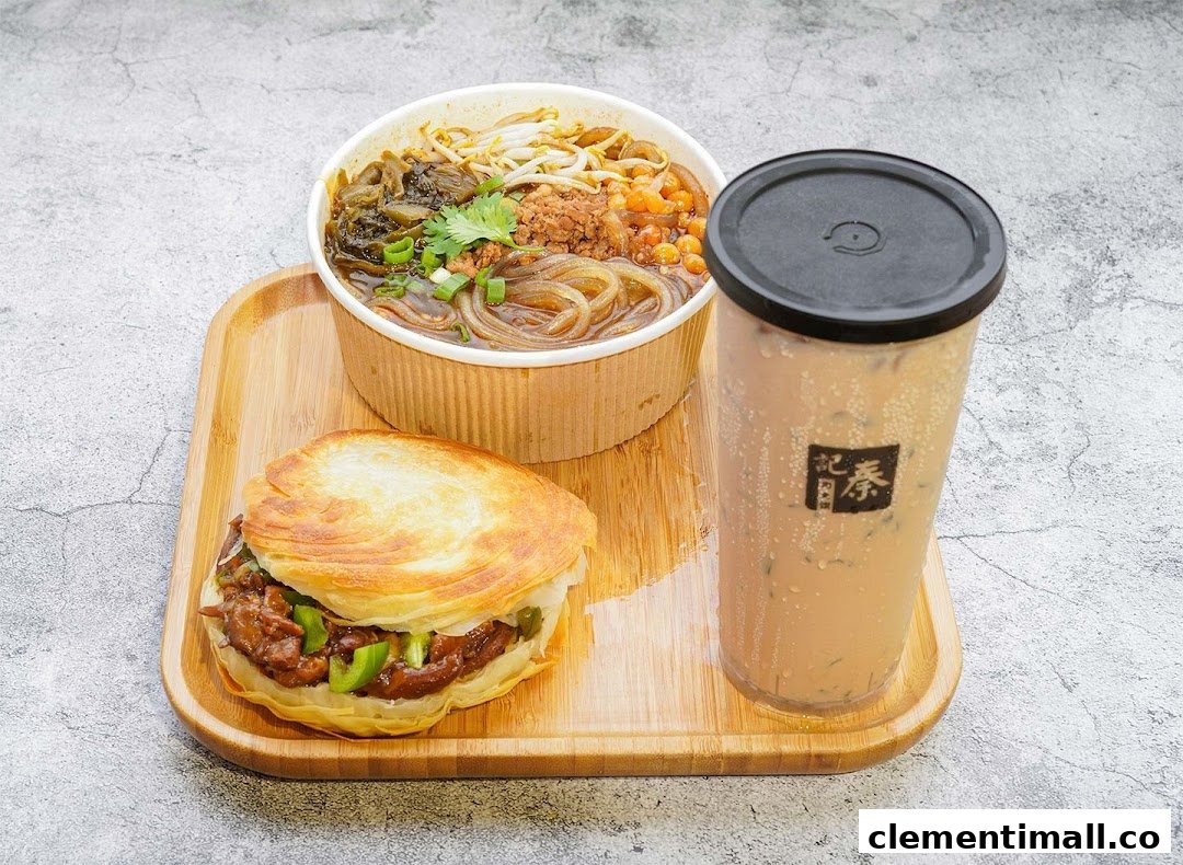 A delicious meal set featuring a rougamo, a noodle soup, and a refreshing beverage on a wooden tray.