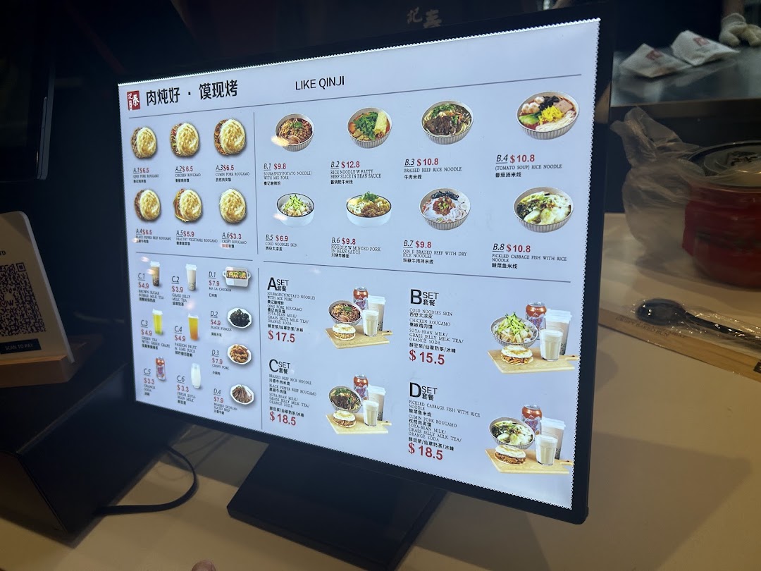 A brightly lit digital menu board displaying various Chinese dishes and drinks with prices.