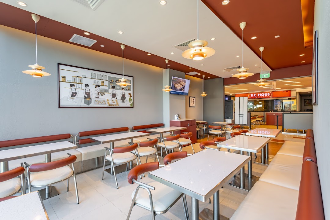 A bright and inviting interior view of Qin Ji Rougamo restaurant with comfortable seating and a unique wall mural.