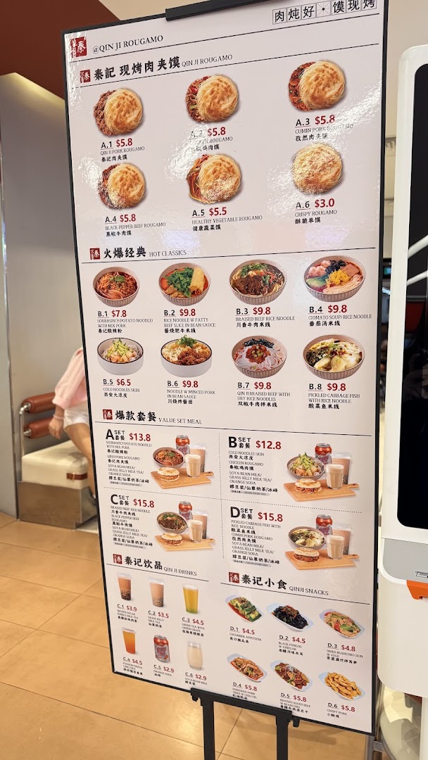 A detailed menu board for Qin Ji Rougamo, showcasing various rougamou, classic dishes, set meals, drinks, and snacks.