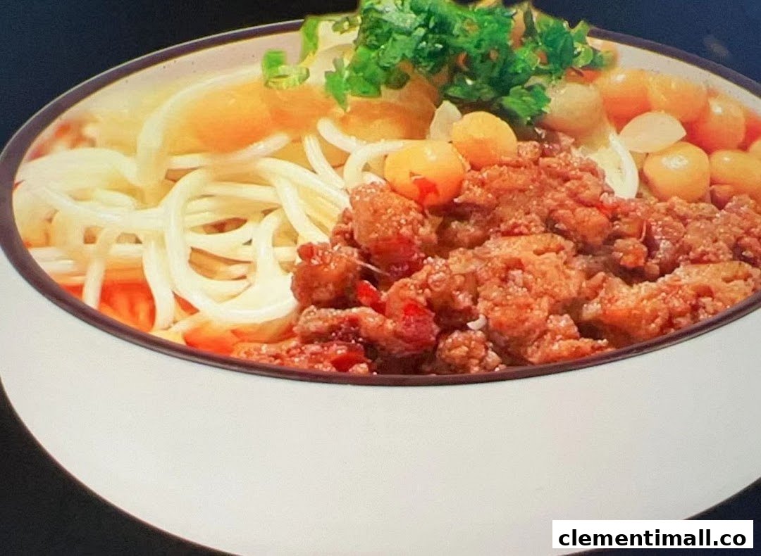 A close-up of a delicious bowl of noodles with minced meat, garnished with fresh herbs.