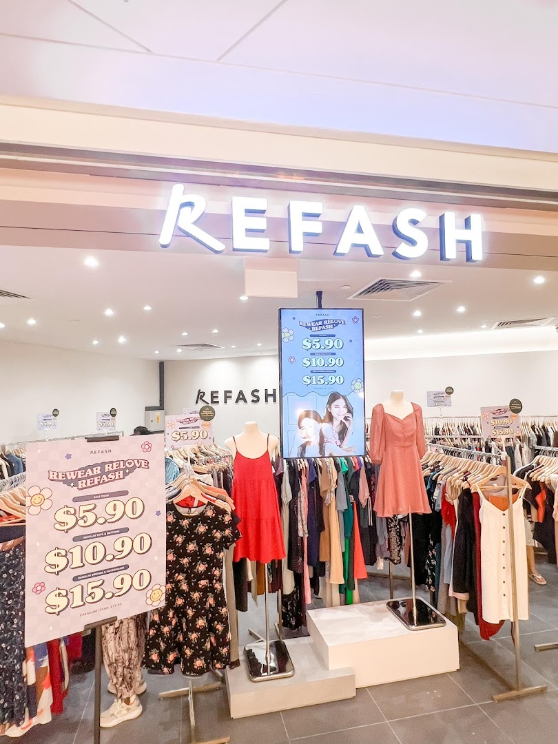The bright entrance of REFASH, a fashion store, showcasing clothing displays and promotional signs.