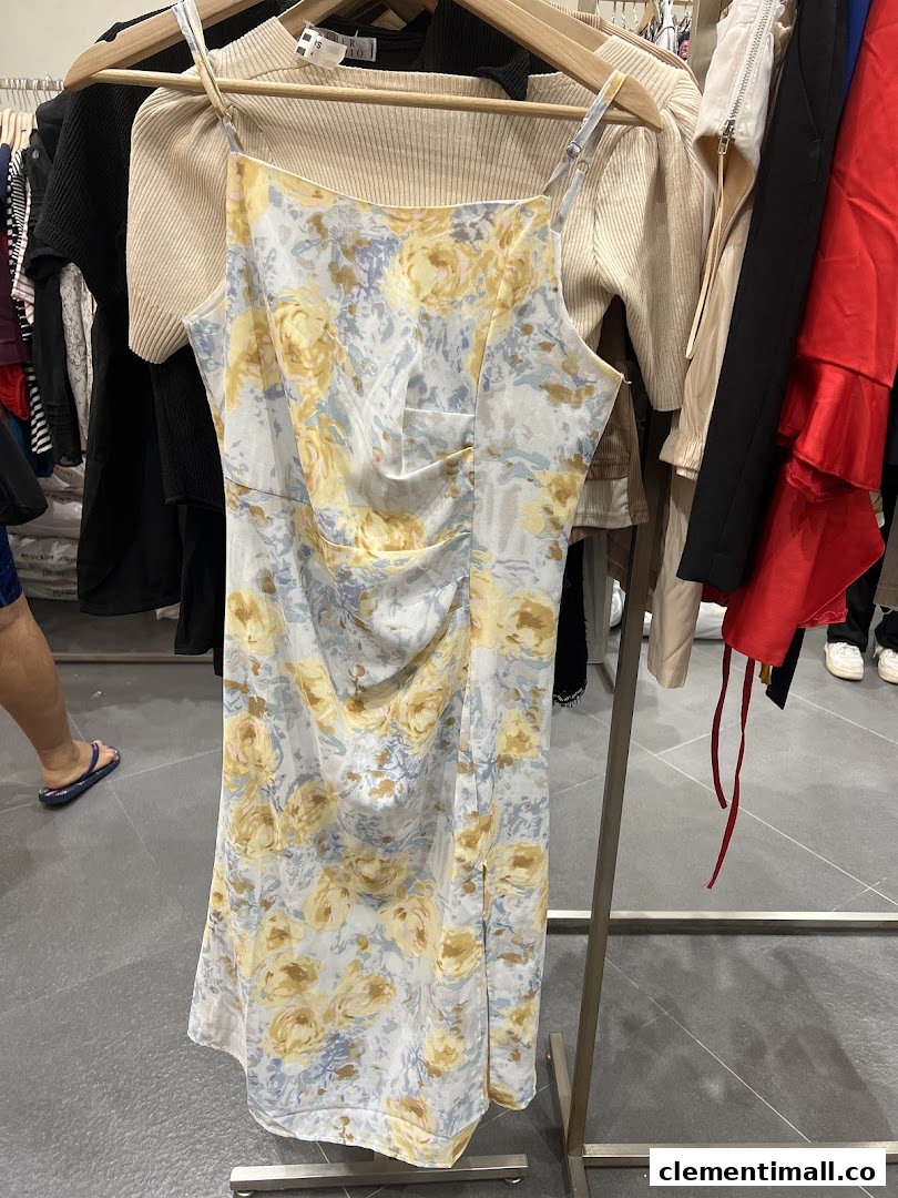A beautiful floral dress with yellow and blue patterns hangs on a rack inside a clothing store.