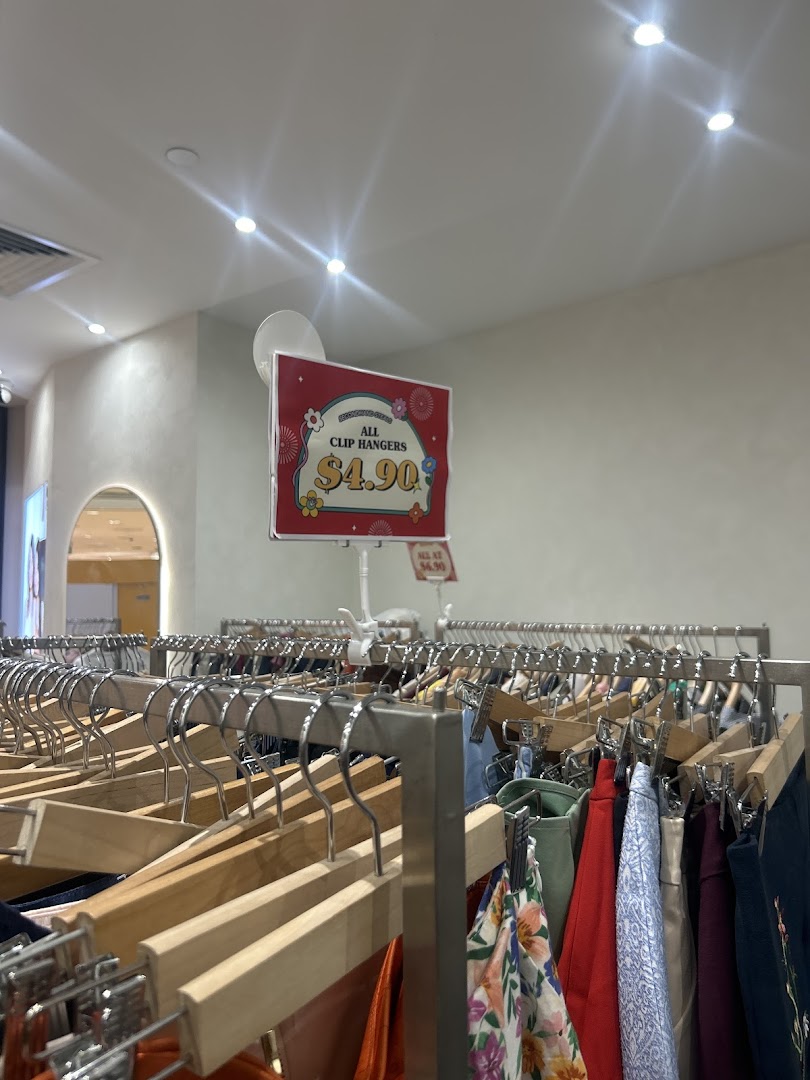 An interior shot of REFASH, showcasing clothing racks filled with preloved apparel and a price sign.