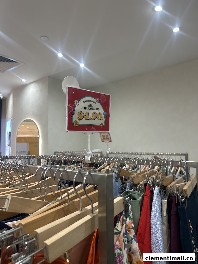 An interior shot of REFASH, showcasing clothing racks filled with preloved apparel and a price sign.