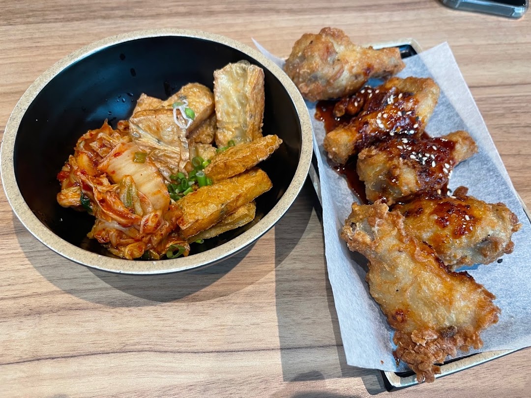 A delicious spread featuring kimchi with fried tofu skin and crispy Korean fried chicken wings.
