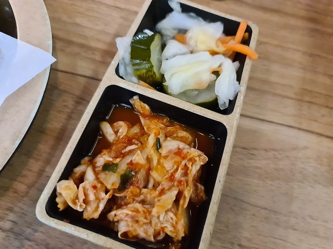 A close-up of traditional Korean banchan, including kimchi and pickled vegetables, served in a divided dish.