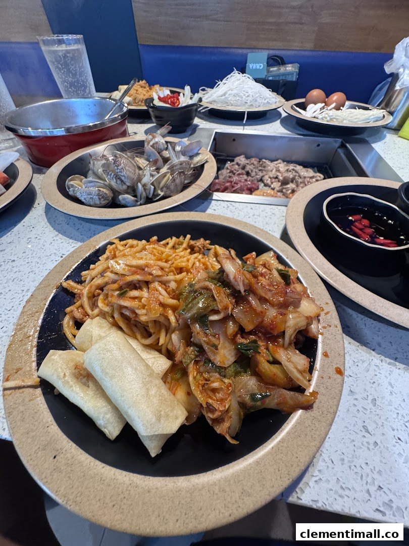 A vibrant table spread at Seoul Garden featuring hotpot ingredients, noodles, kimchi, and spring rolls.