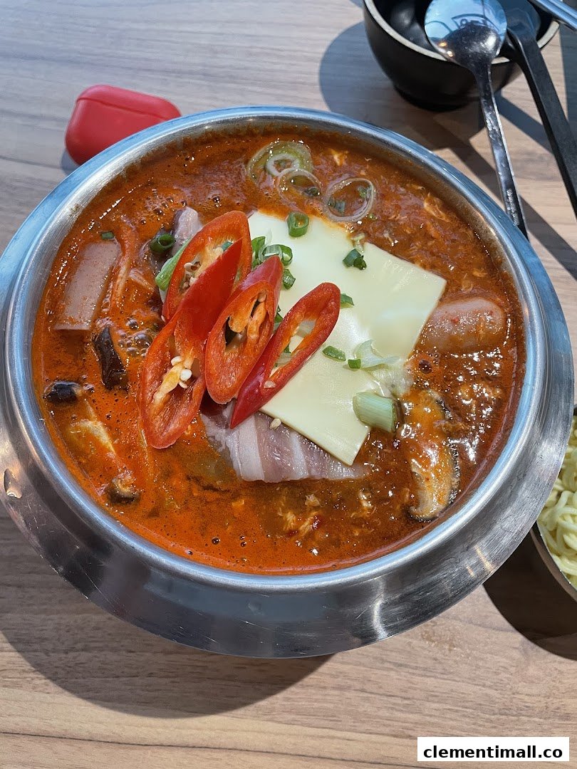 A vibrant Korean hotpot or stew with chili, cheese, and various ingredients in a metal pot.