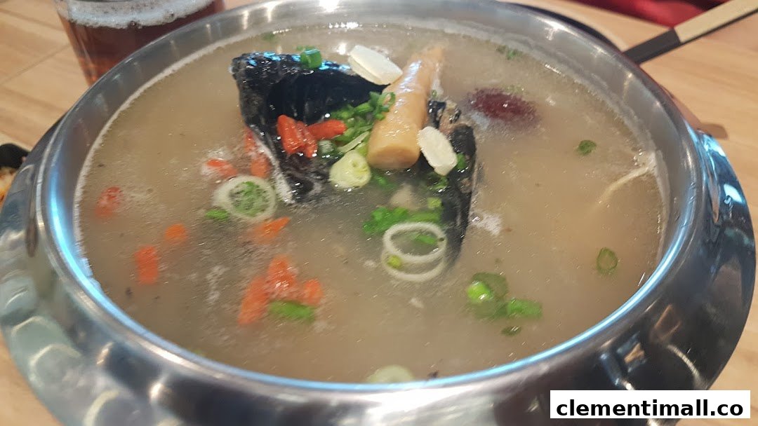 A close-up of a hearty Korean soup or hot pot dish, featuring dark meat, bamboo shoots, and goji berries.