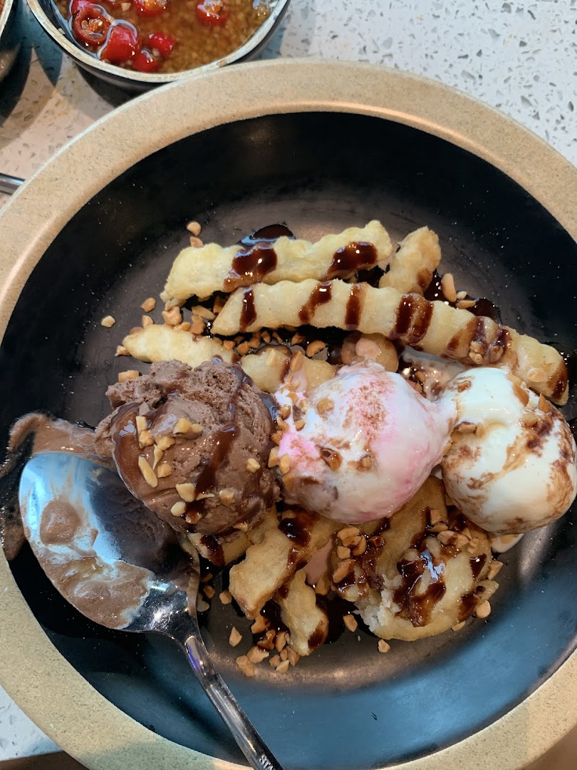 A delightful dessert featuring scoops of ice cream, waffle fries, chocolate sauce, and chopped nuts.