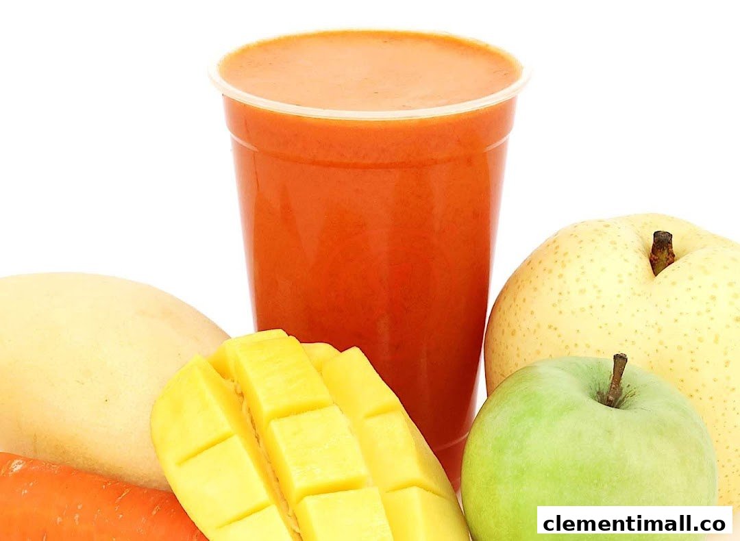 A vibrant cup of fresh juice surrounded by mango, carrot, apple, and pear on a white background.