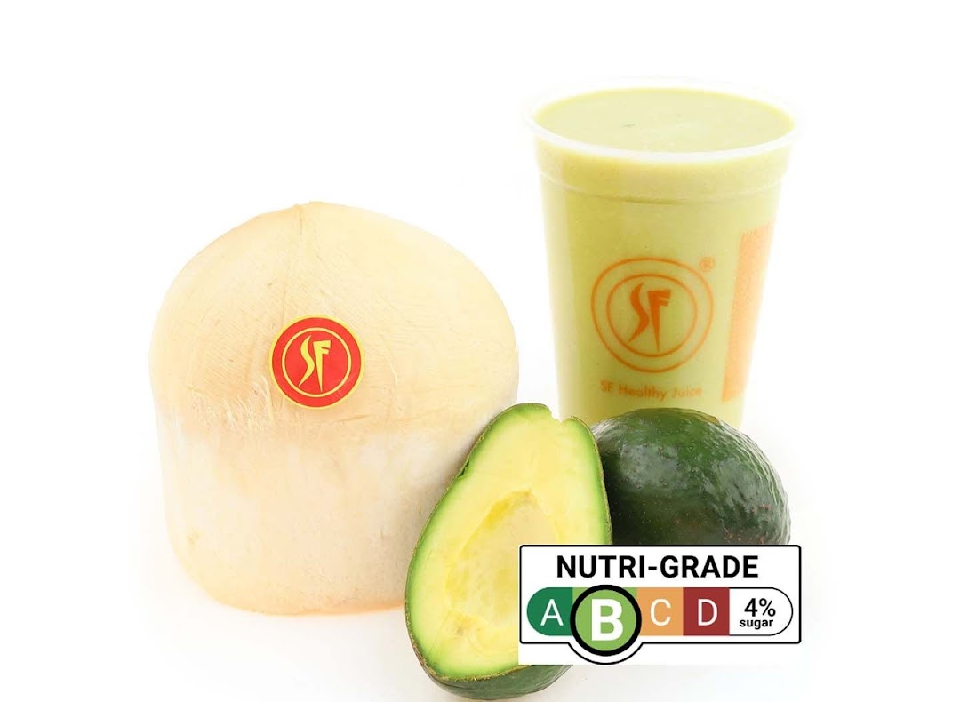 A fresh coconut, whole and sliced avocados, and a green smoothie with a nutri-grade label.