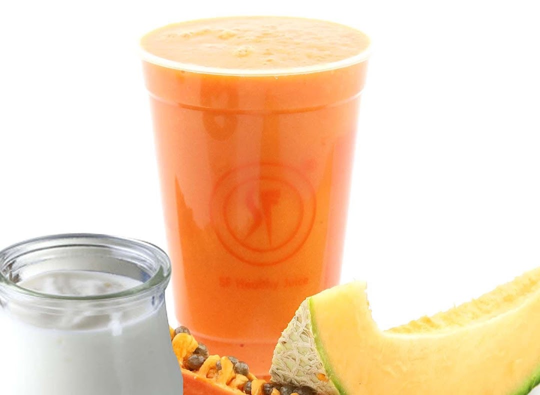 A vibrant orange juice with fresh papaya, melon, and yogurt, showcasing healthy ingredients.