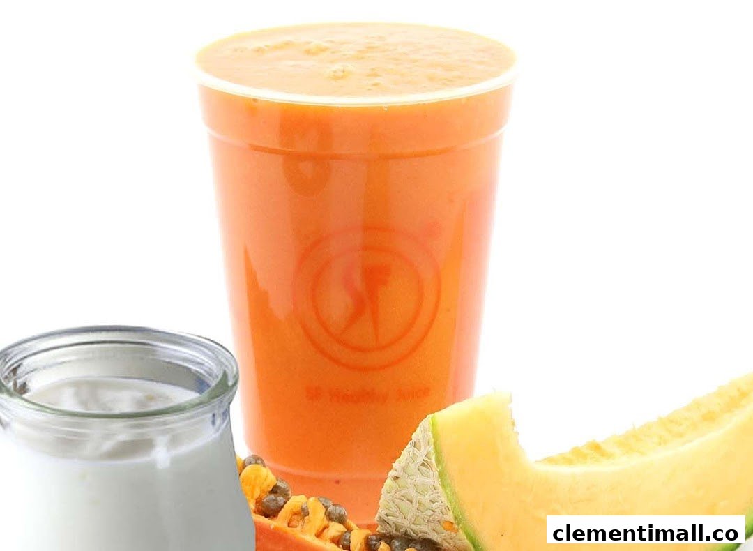A vibrant orange juice with fresh papaya, melon, and yogurt, showcasing healthy ingredients.