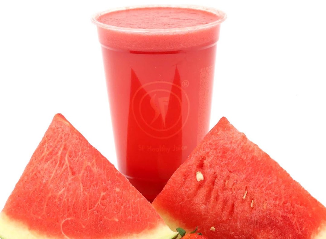 A vibrant red watermelon juice in a clear cup, flanked by fresh watermelon slices.