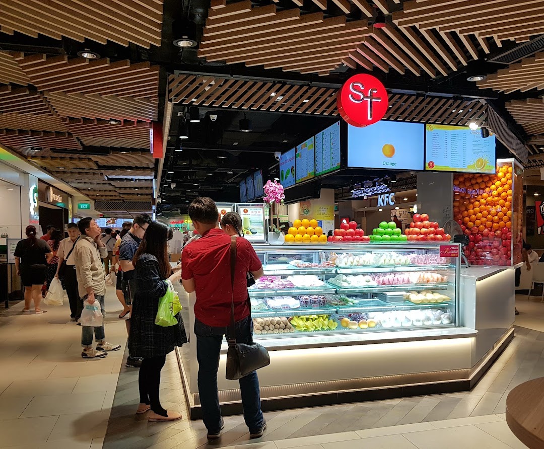 A vibrant fruit and juice stall in a mall, showcasing fresh produce and prepared fruit.