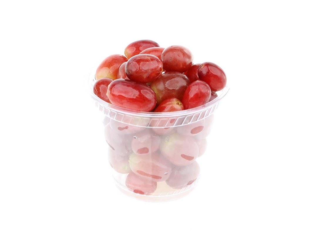 A clear plastic cup filled with vibrant red grapes, ready for a healthy snack.
