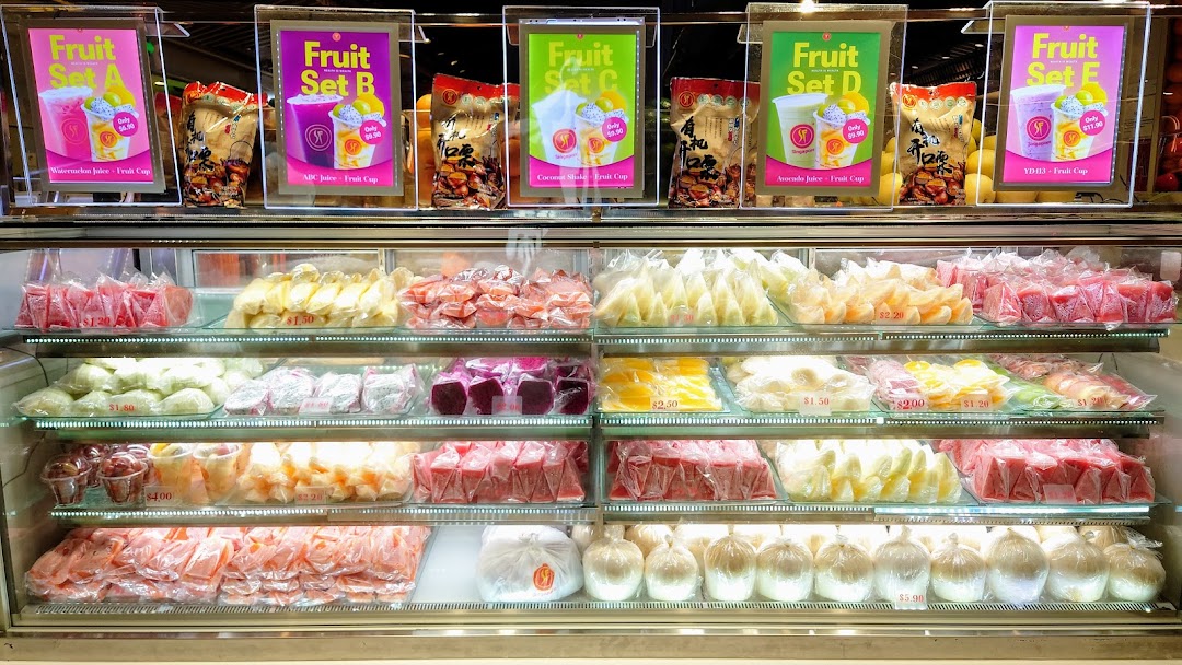 A vibrant display of fresh pre-cut fruits, juices, and fruit sets in a refrigerated case.