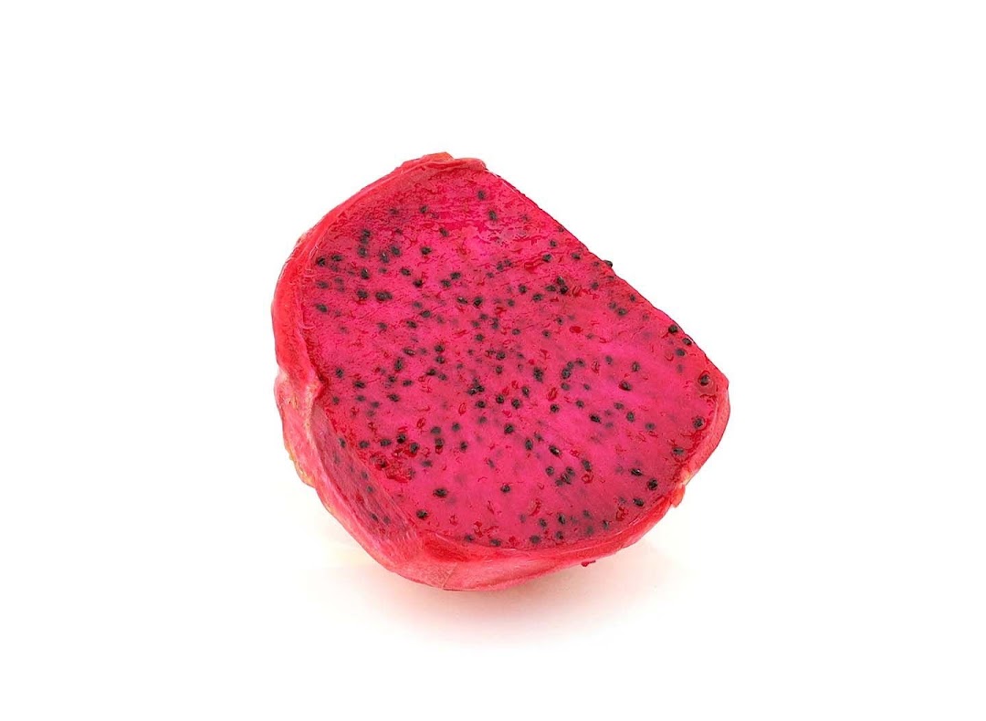 A vibrant red dragon fruit slice with black seeds on a white background.