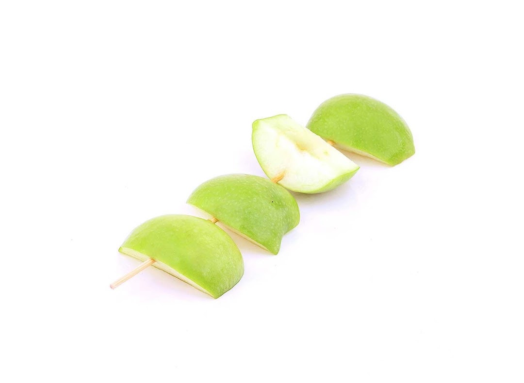 Fresh green apple slices on a skewer, ready for a refreshing snack.