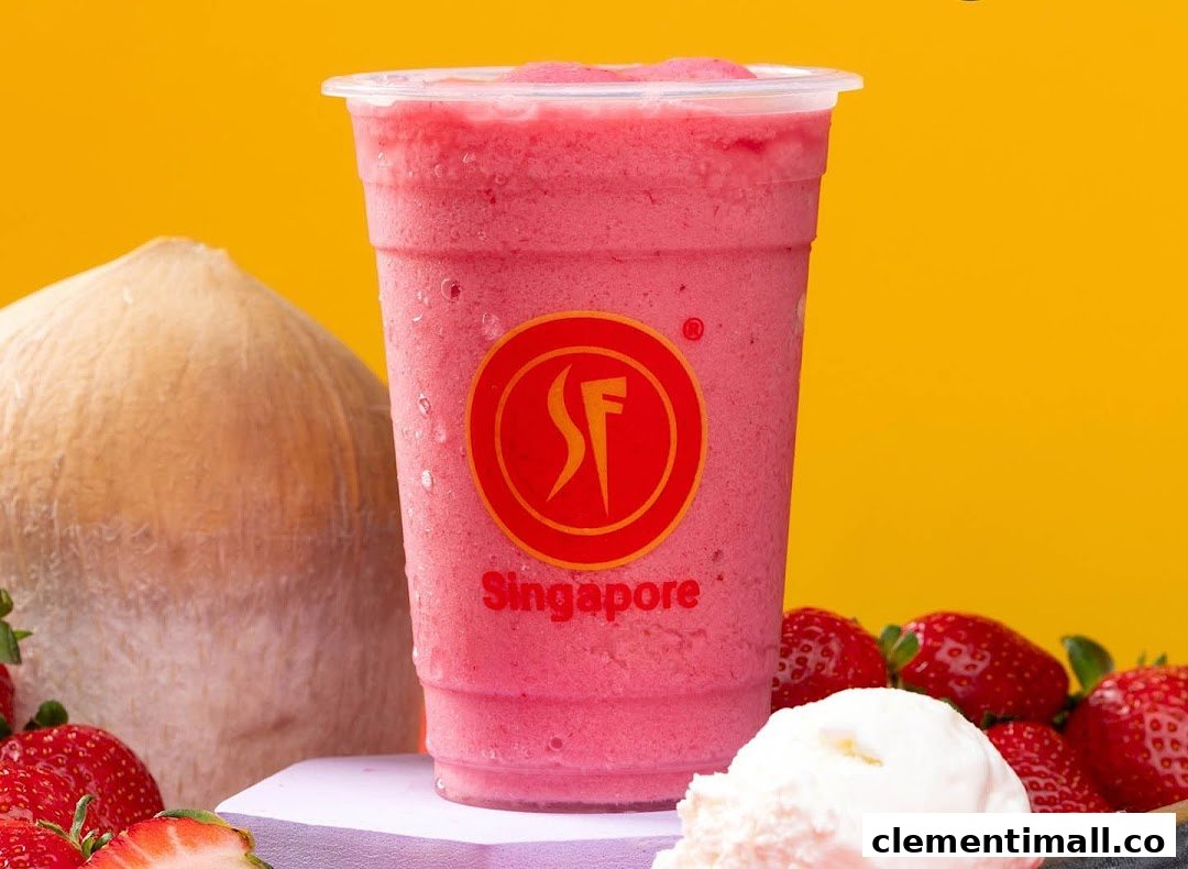 A vibrant pink fruit smoothie with strawberries, coconut, and ice cream against a yellow background.