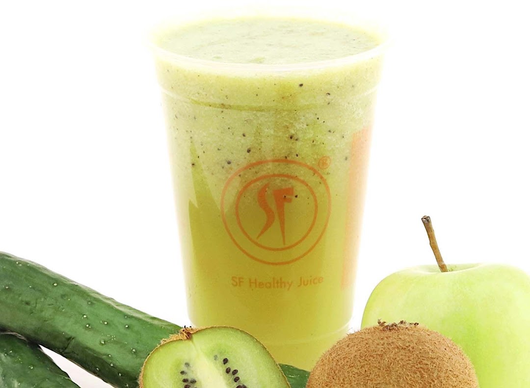 A vibrant green smoothie in a clear cup, surrounded by fresh kiwi, cucumber, and a green apple.