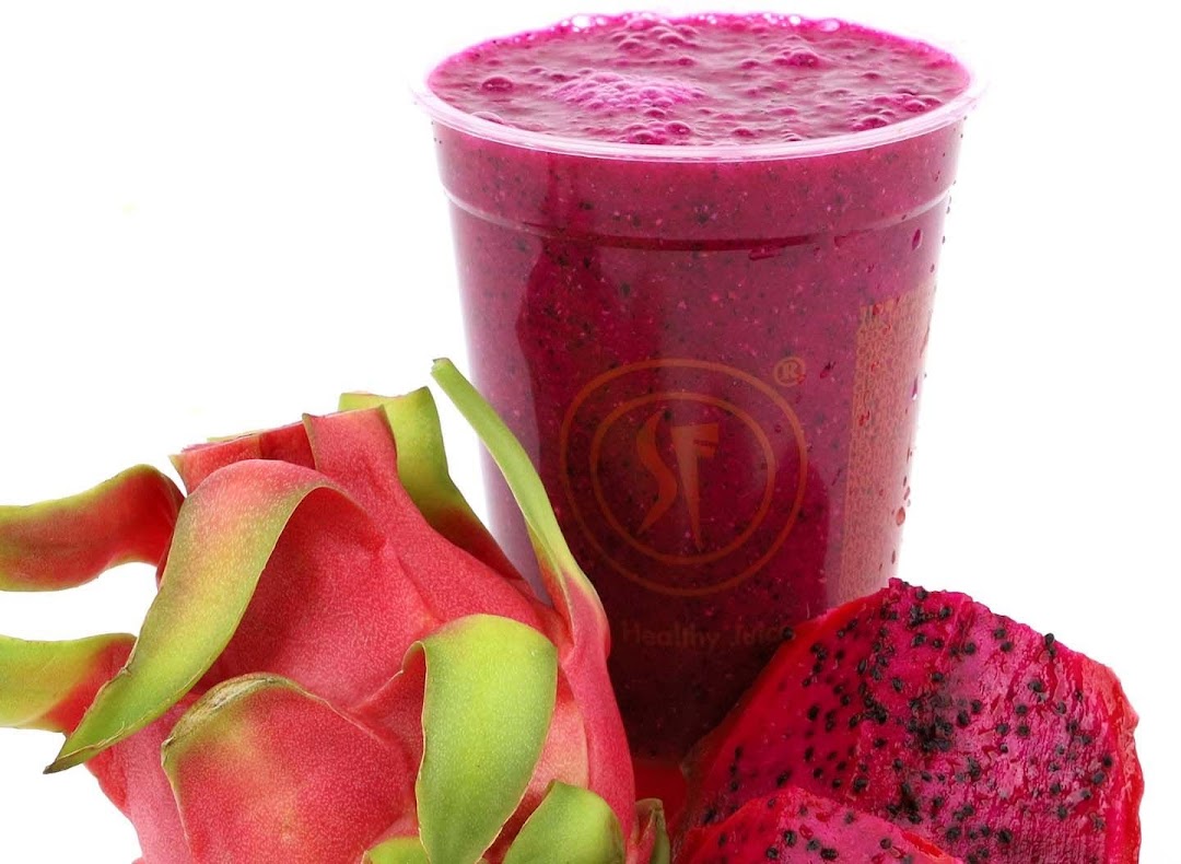 A vibrant dragon fruit smoothie in a cup, accompanied by fresh dragon fruit.