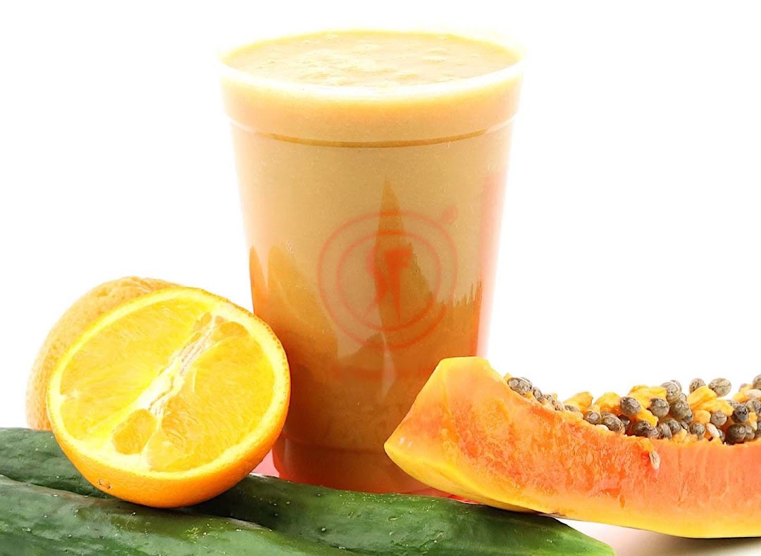 A refreshing fruit smoothie in a cup, surrounded by fresh orange, papaya, and cucumber.