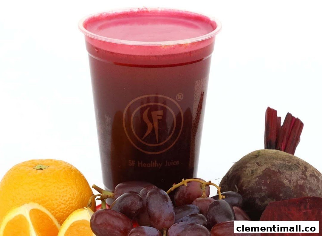 A vibrant red juice in a clear cup, surrounded by fresh oranges, grapes, and beetroot.