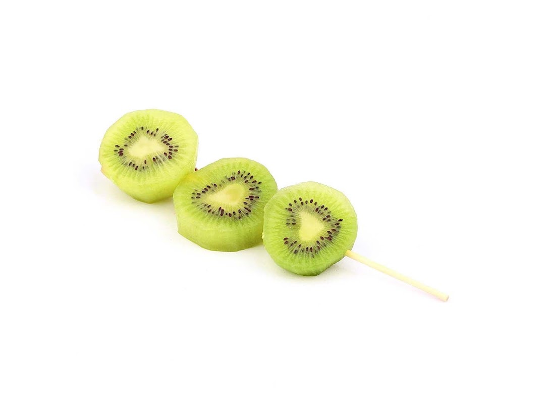 Three fresh kiwi slices on a stick, showcasing a healthy snack option.