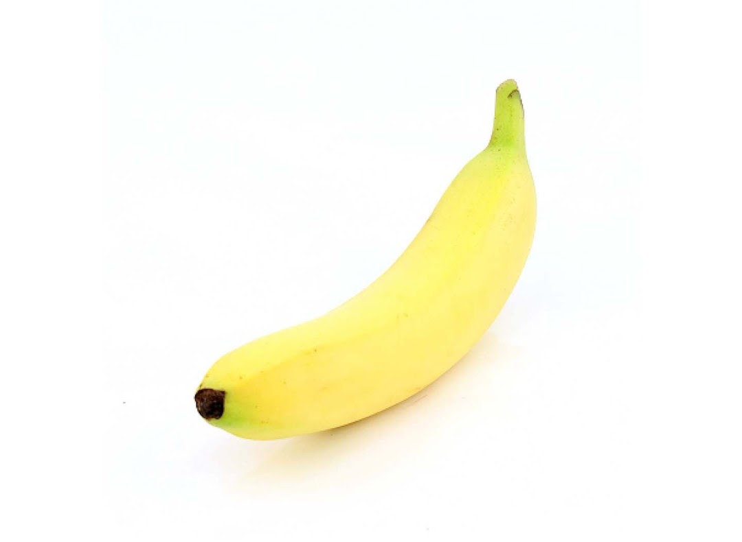A single ripe yellow banana is displayed against a clean white background.