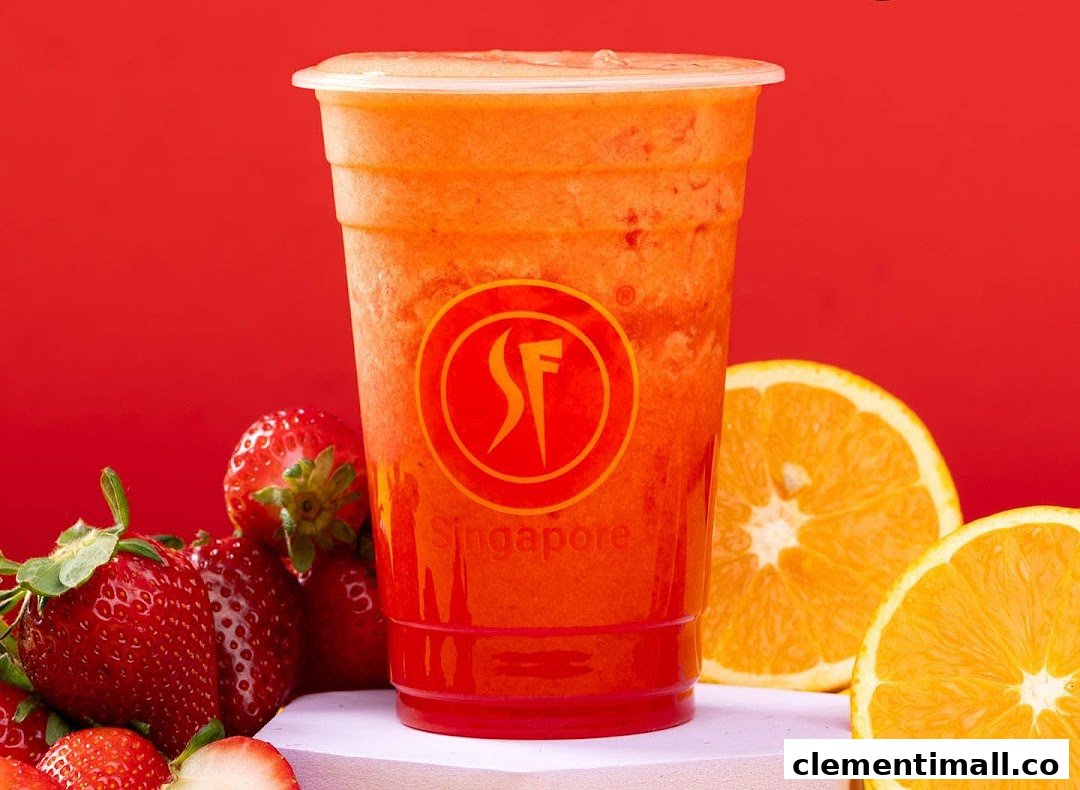 A vibrant fruit juice in a cup, surrounded by fresh strawberries and orange slices.