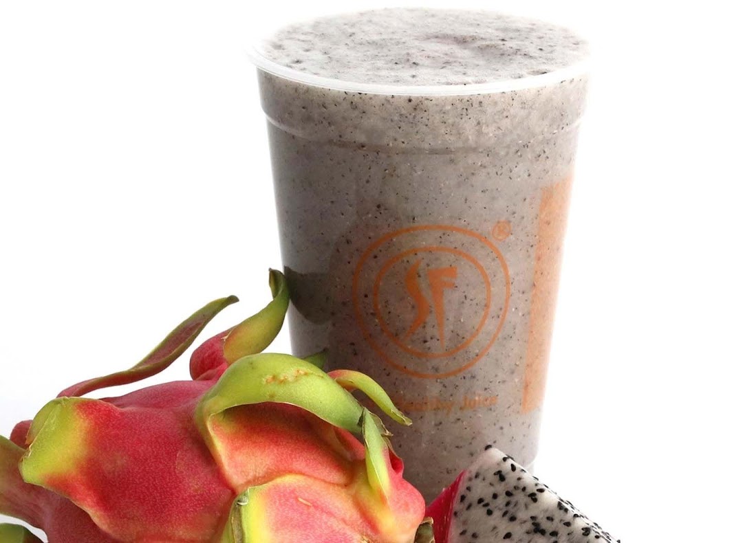 A refreshing dragon fruit smoothie in a clear cup, with fresh dragon fruit beside it.