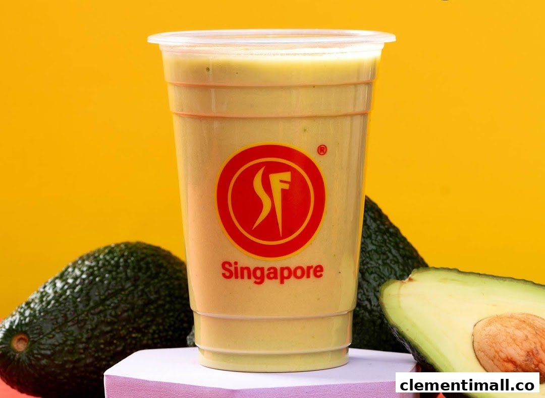 A creamy avocado smoothie in a clear cup, surrounded by fresh whole and halved avocados.