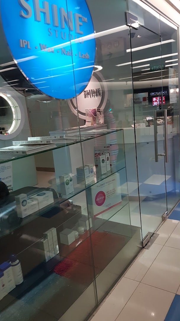The glass storefront of SHINE Studio, featuring its blue circular logo and services like IPL, Wax, Nail, and Lash.