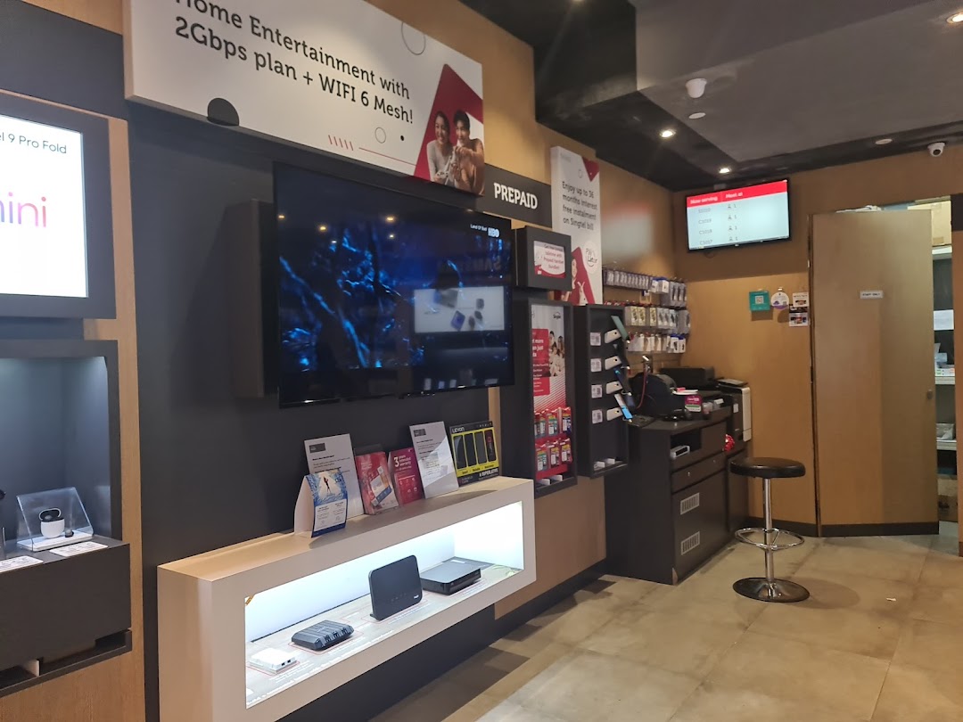 Interior view of a Singtel shop showcasing mobile devices, home entertainment plans, and a customer service area.
