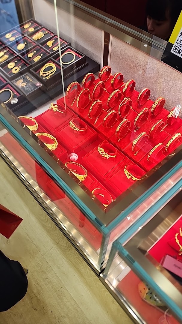 Close-up of gold jewelry, including bangles and pendants, displayed in glass cases with red velvet at SK Jewellery.