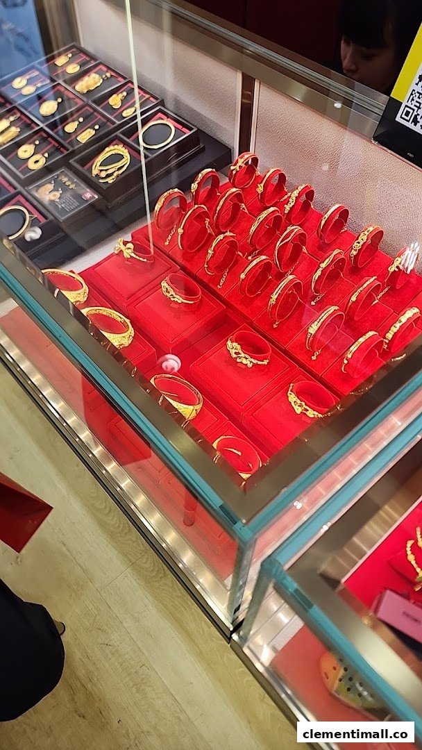 Close-up of gold jewelry, including bangles and pendants, displayed in glass cases with red velvet at SK Jewellery.