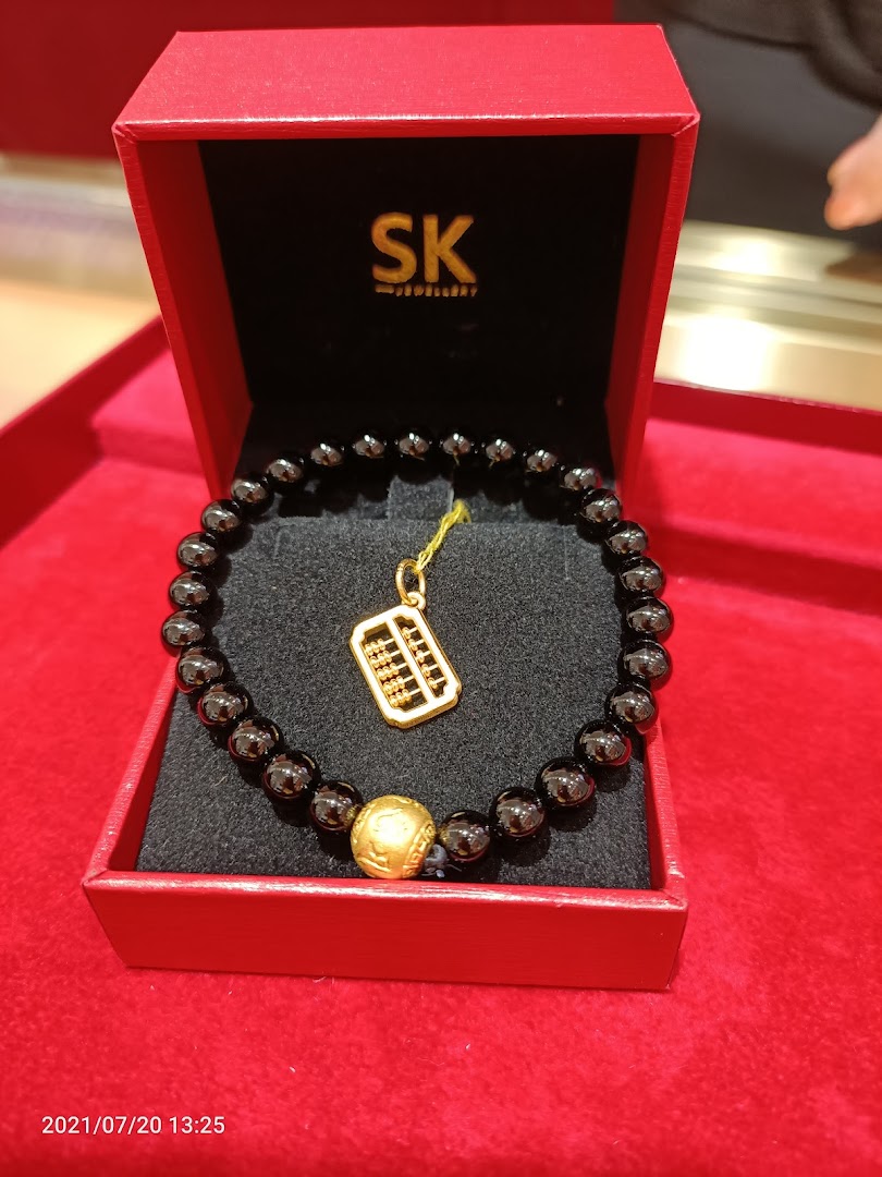 A black beaded bracelet with a gold abacus charm and bead displayed in a red SK Jewellery box.
