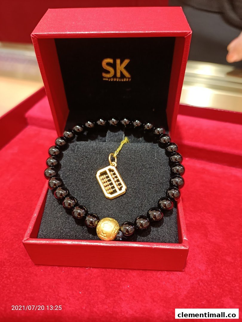A black beaded bracelet with a gold abacus charm and bead displayed in a red SK Jewellery box.