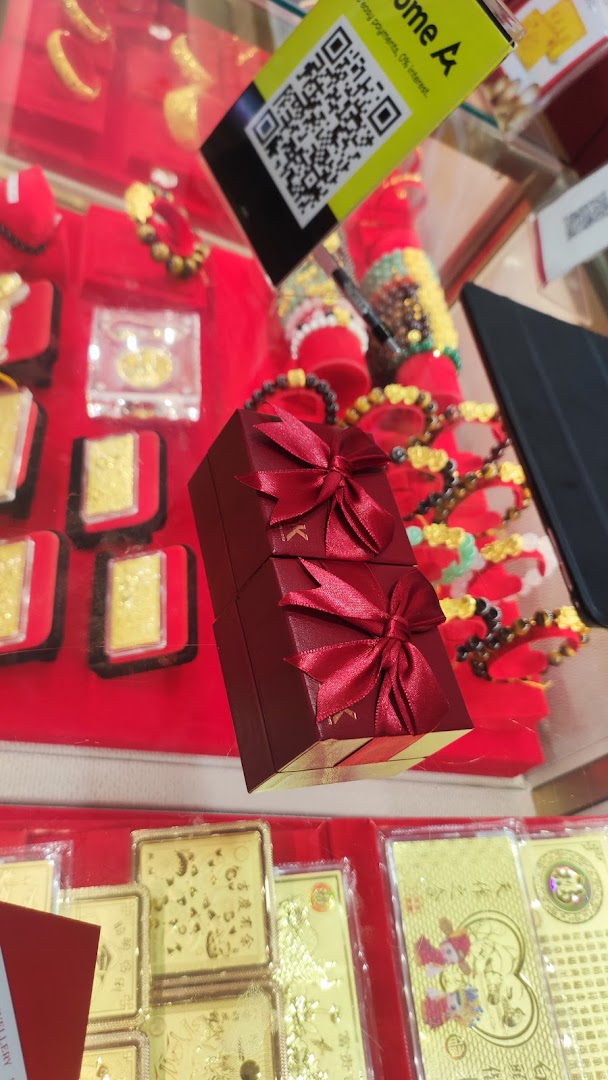 A display case at SK Jewellery showcasing gold bars, bracelets, and elegant red gift boxes.