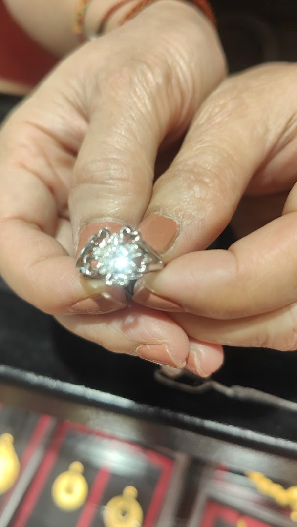 A person's hands hold a sparkling silver ring with a floral design, likely in a jewelry store.