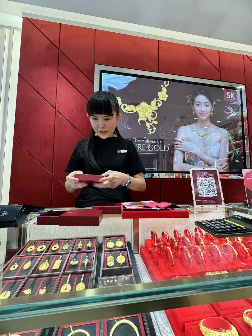 A staff member at SK Jewellery assists a customer amidst displays of exquisite gold jewelry.