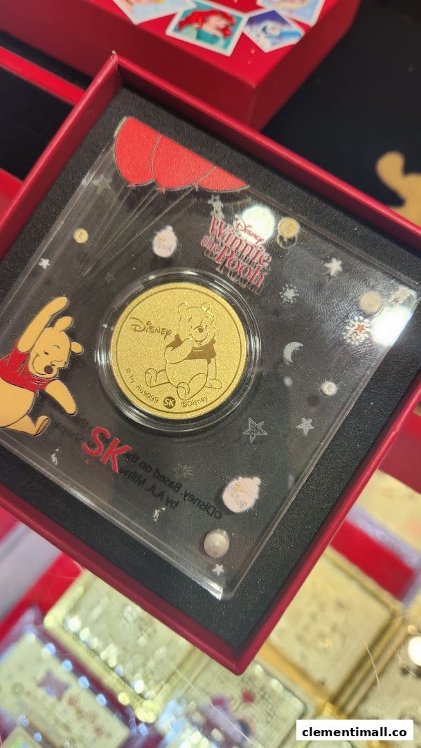 A close-up of a Disney Winnie the Pooh gold coin in its display case from SK Jewellery.