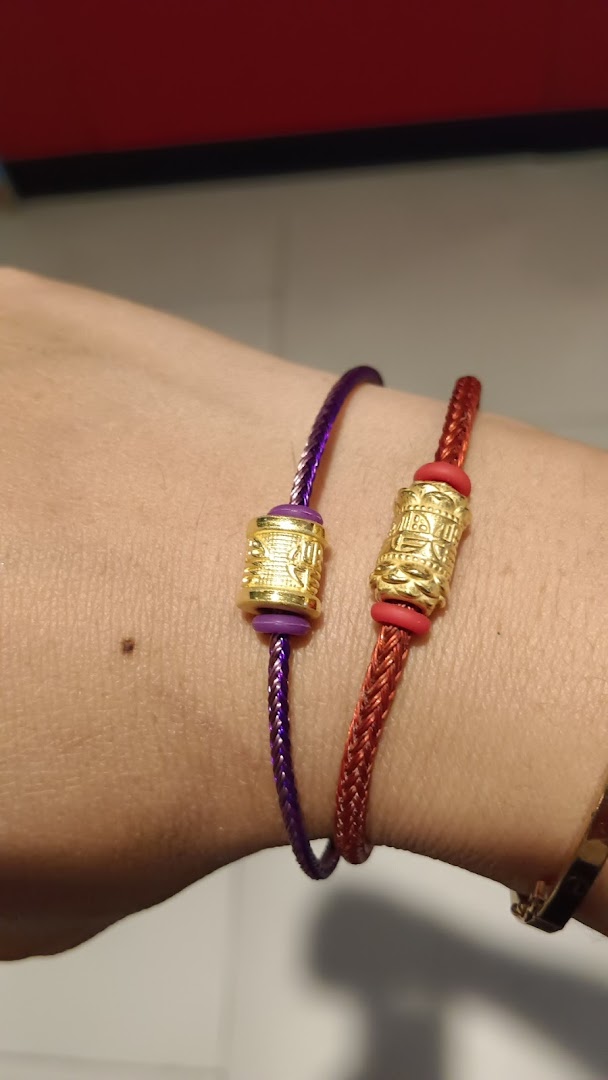 Two colorful braided bracelets with intricate gold beads on a person's wrist.